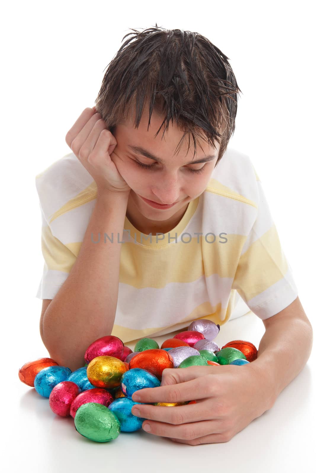 A boy looking down at lots of colourful bright chocolate easter eggs.