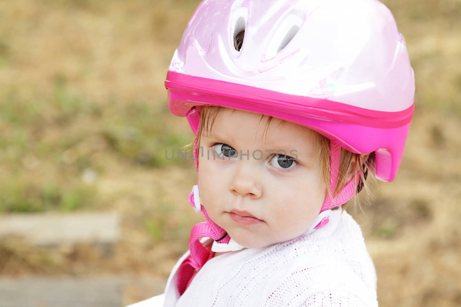 Cute toddler girl with pink helmet outdoors