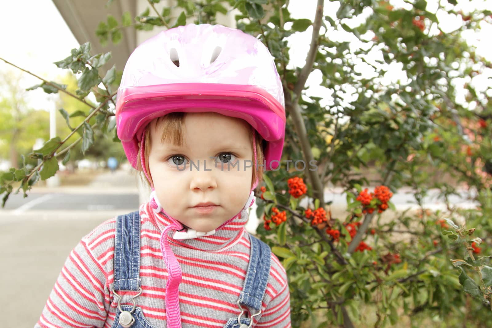 Cute little girl with pink bicycle helmet outdoors