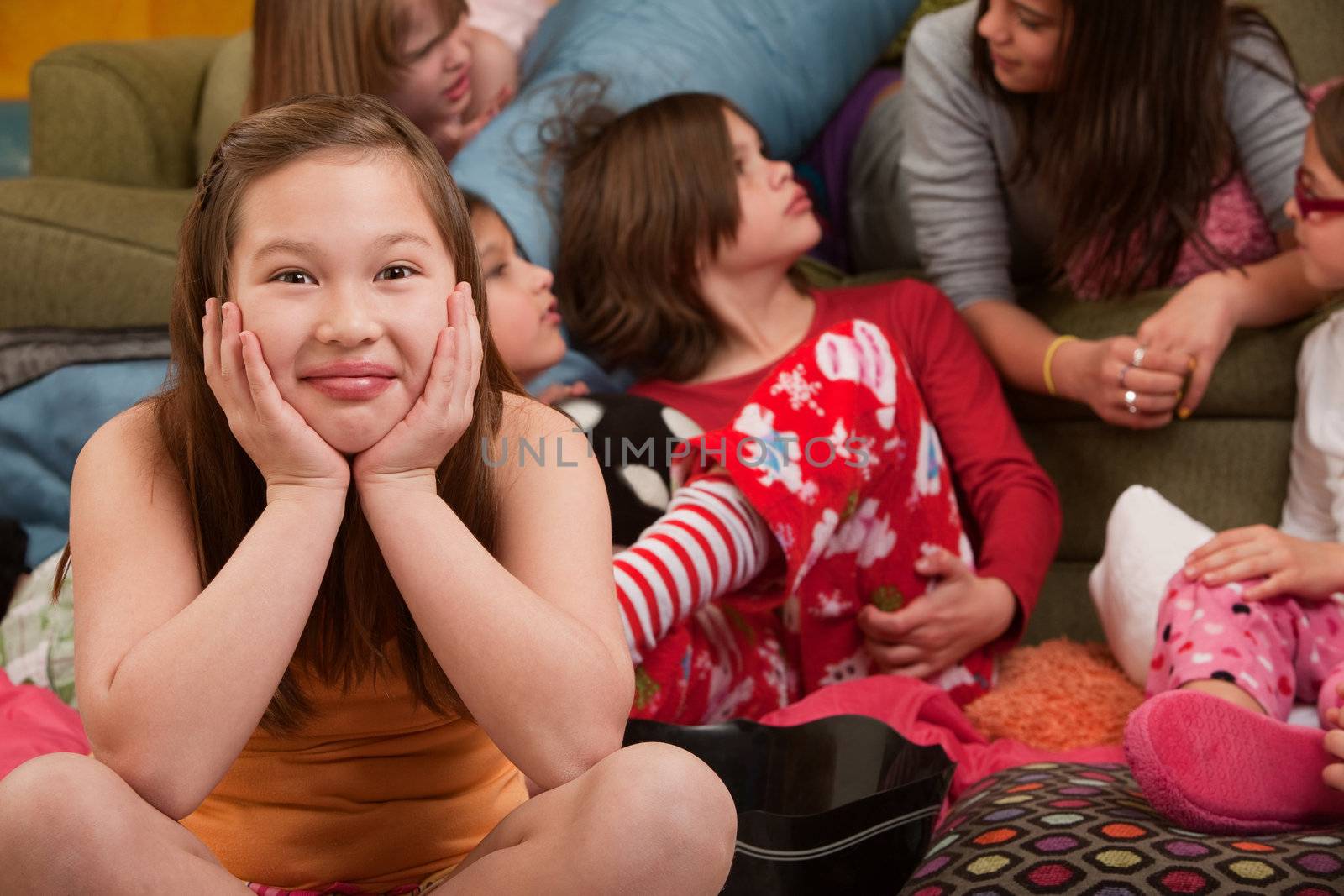 Happy girl with friends seated on floor at a sleepover