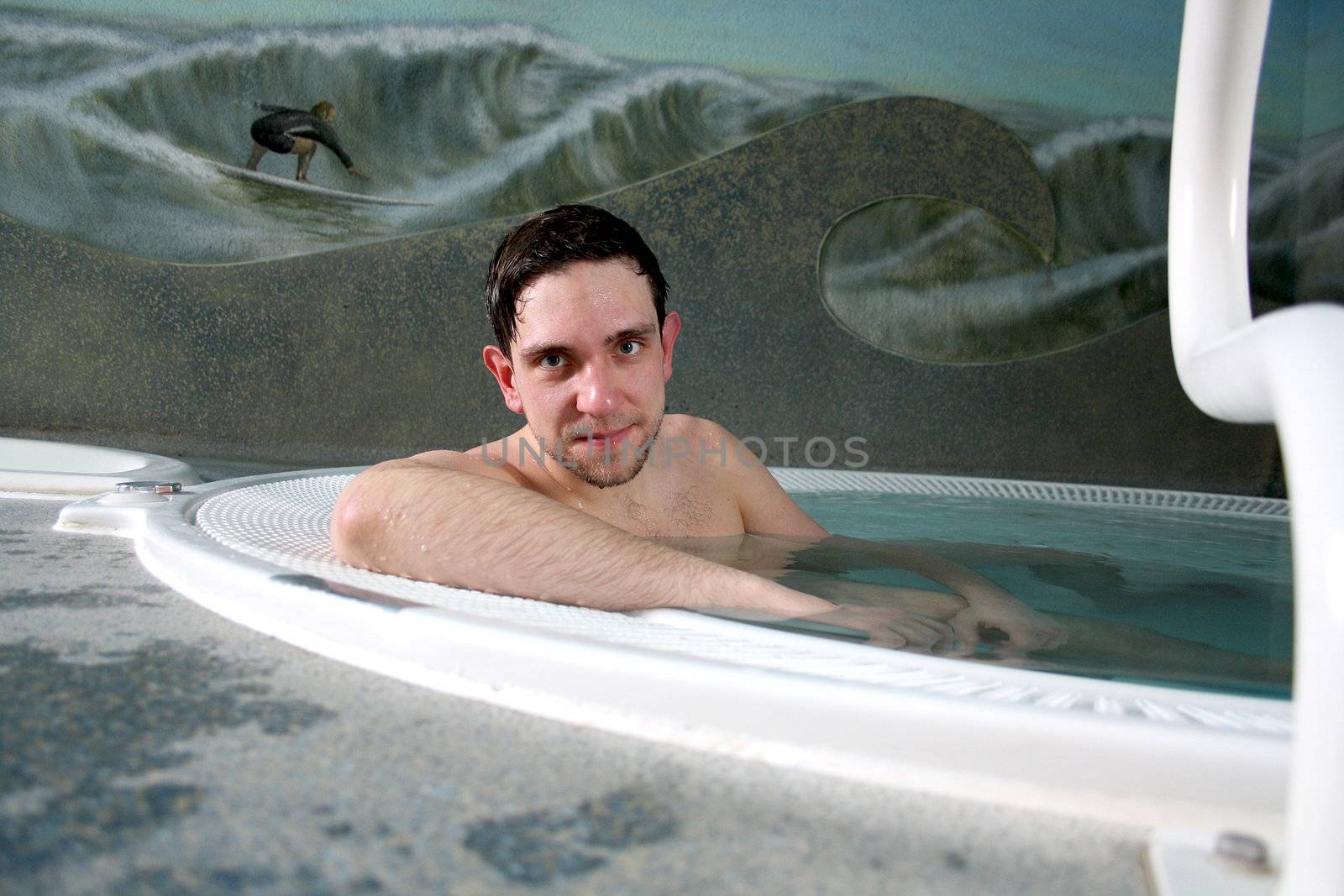 A pretty boy is lying relaxed in the pool 