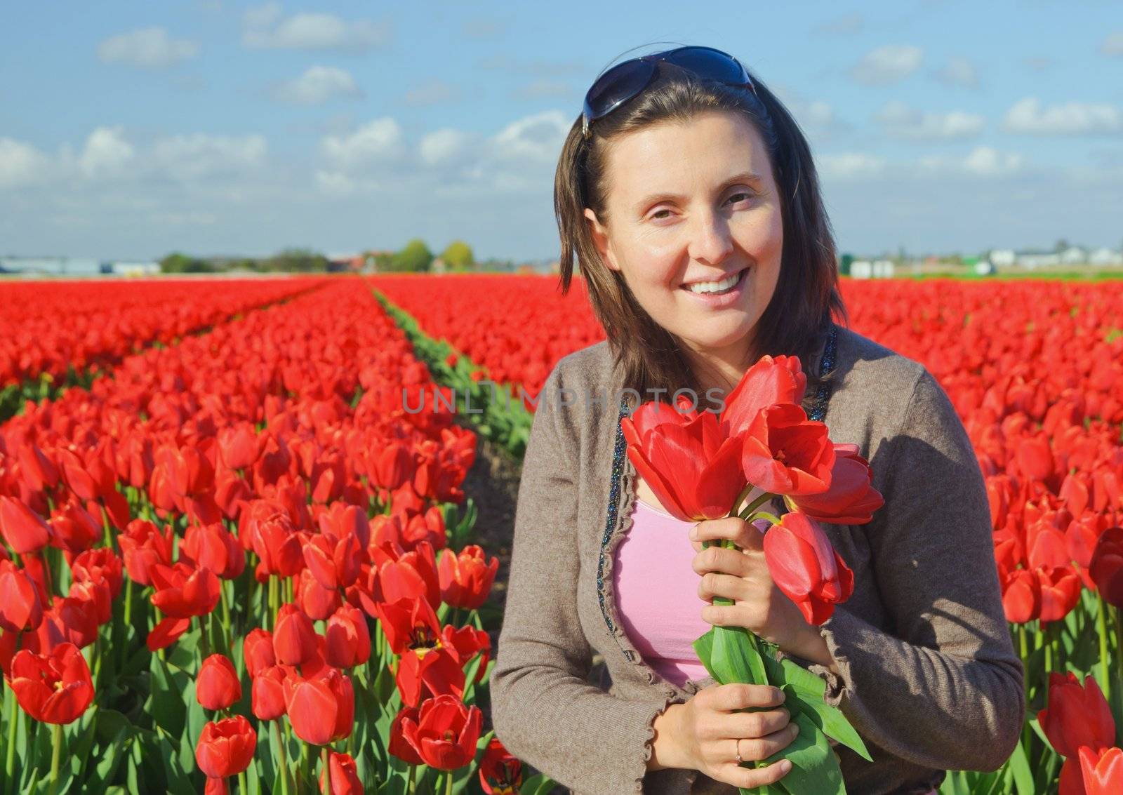Happy women with red tulip in tulips field.