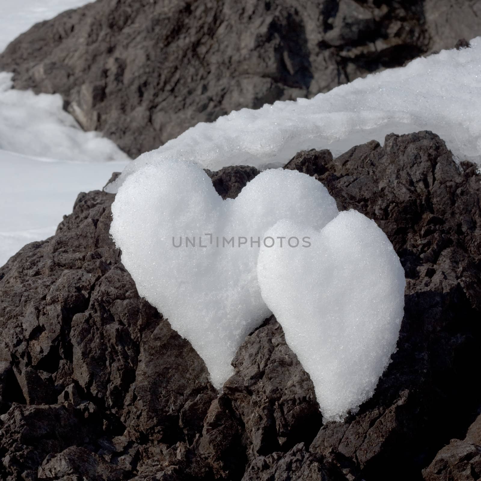Two Valentine�s Day Hearts formed from snow on rock surface.