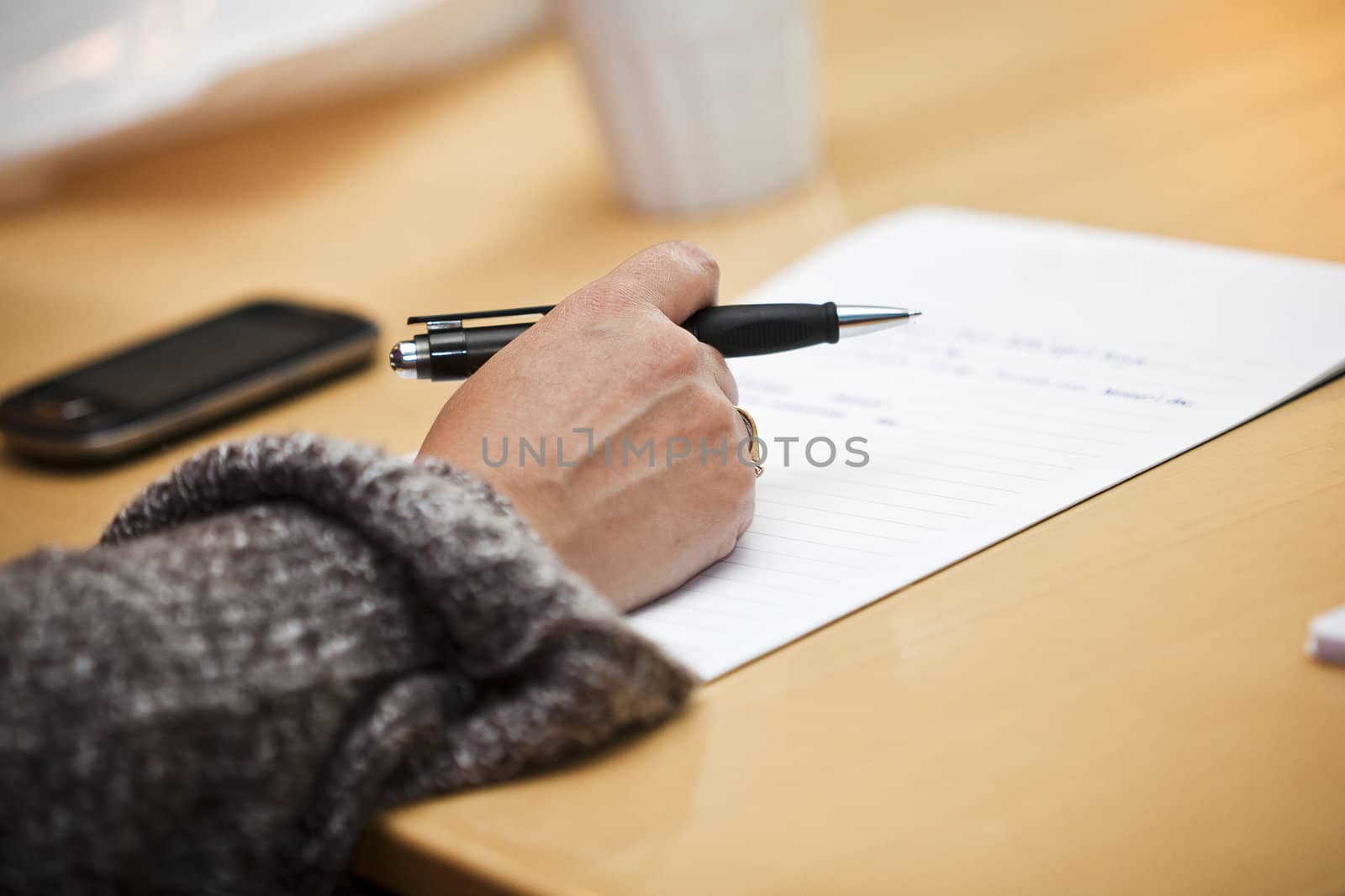 Human hand holding a pencil on a table