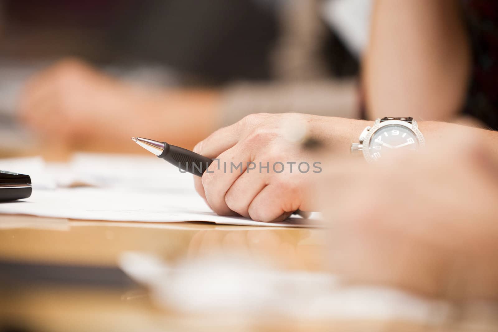 Human hand holding a pencil on a table