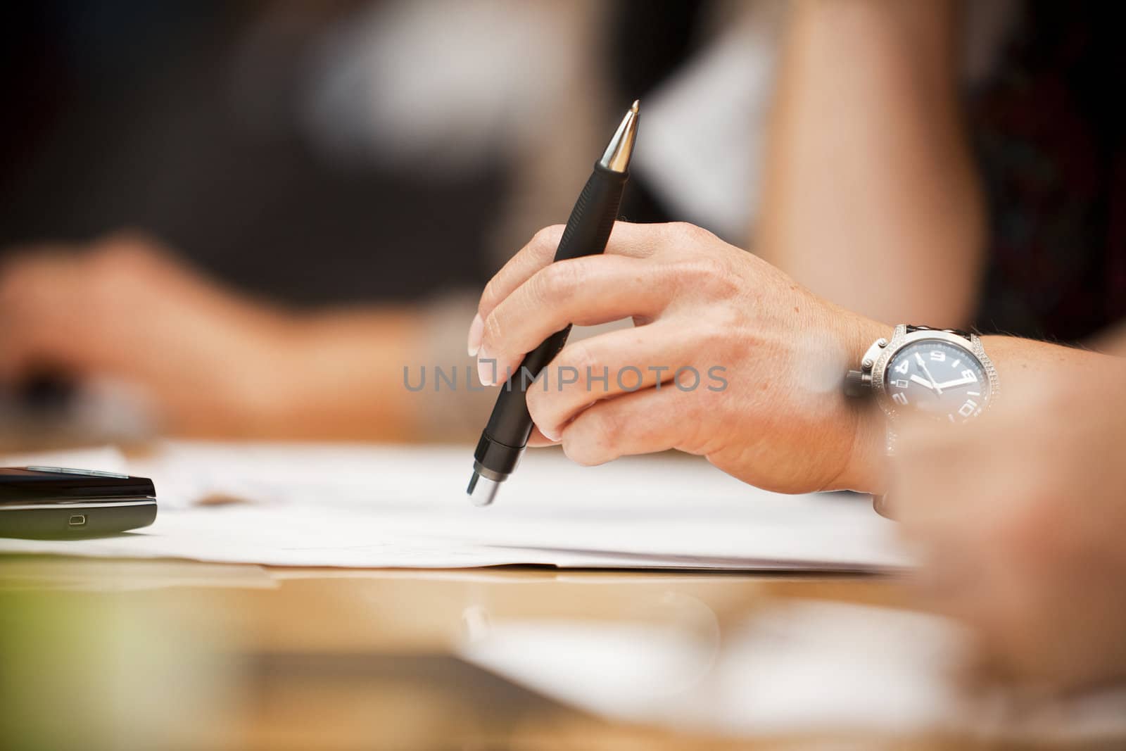 Human hand holding a pencil on a table