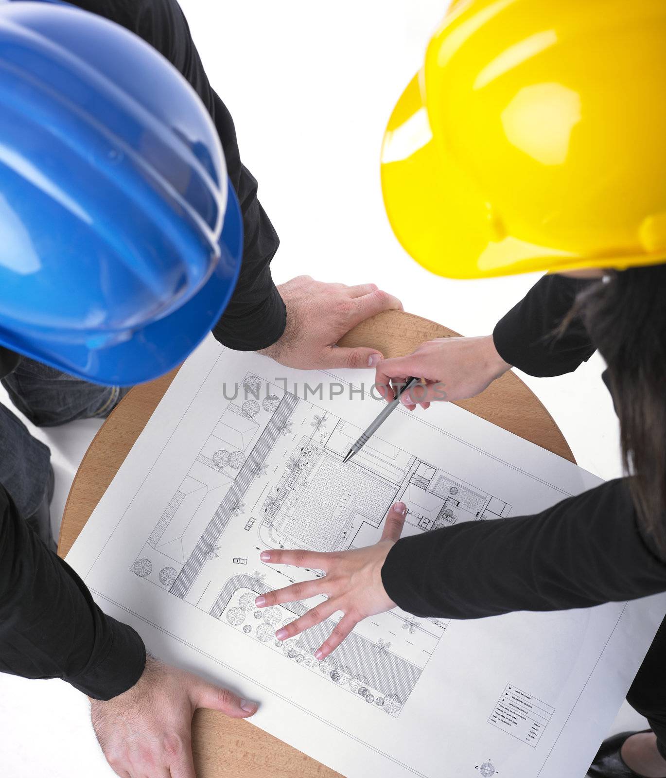 Two architects with hard hats and plan on meeting in office
