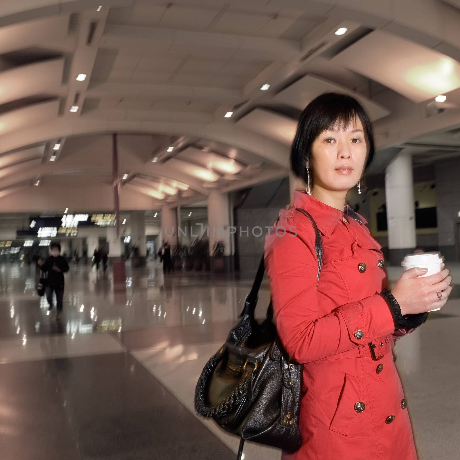 Asian woman holding cup of coffee, half length closeup portrait in modern public station.