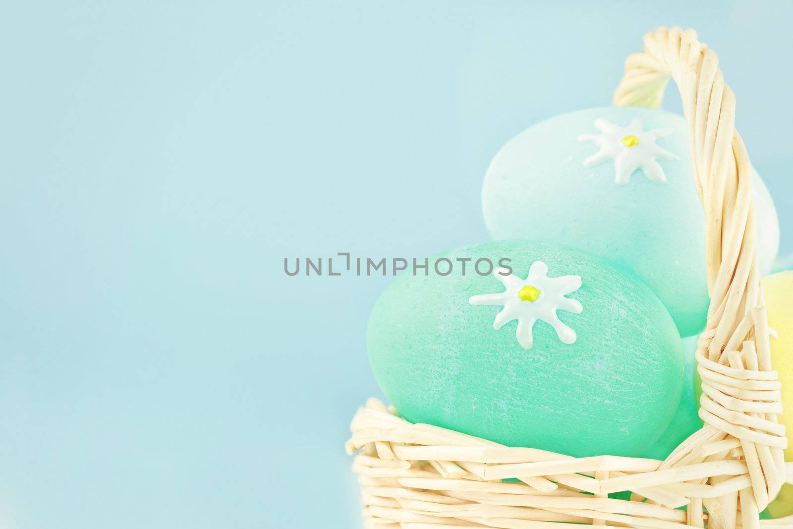 Basket full of Easter eggs in a basket against a blue background with room for copyspace. Extreme shallow DOF.
