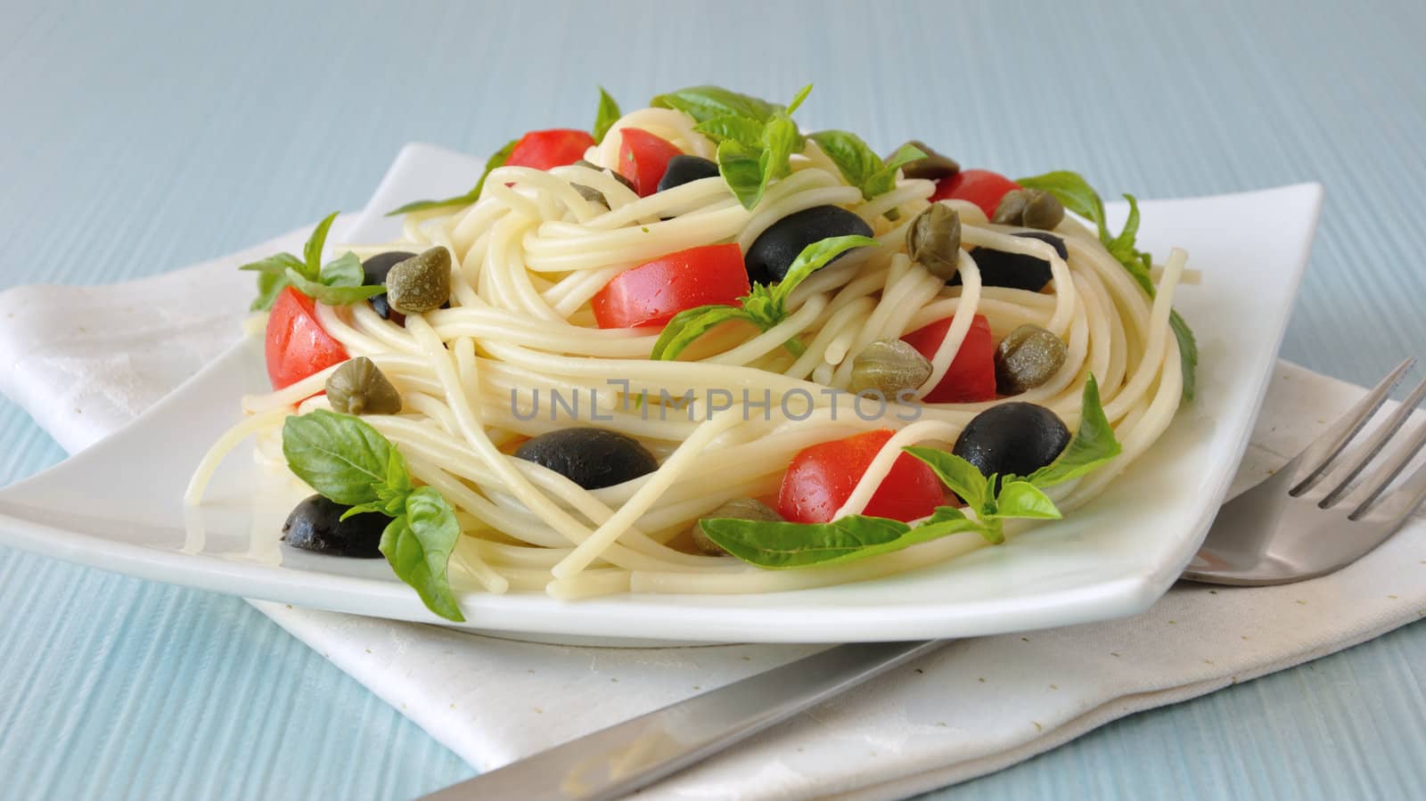 Spaghetti with tomato slices and olives, capers and basil