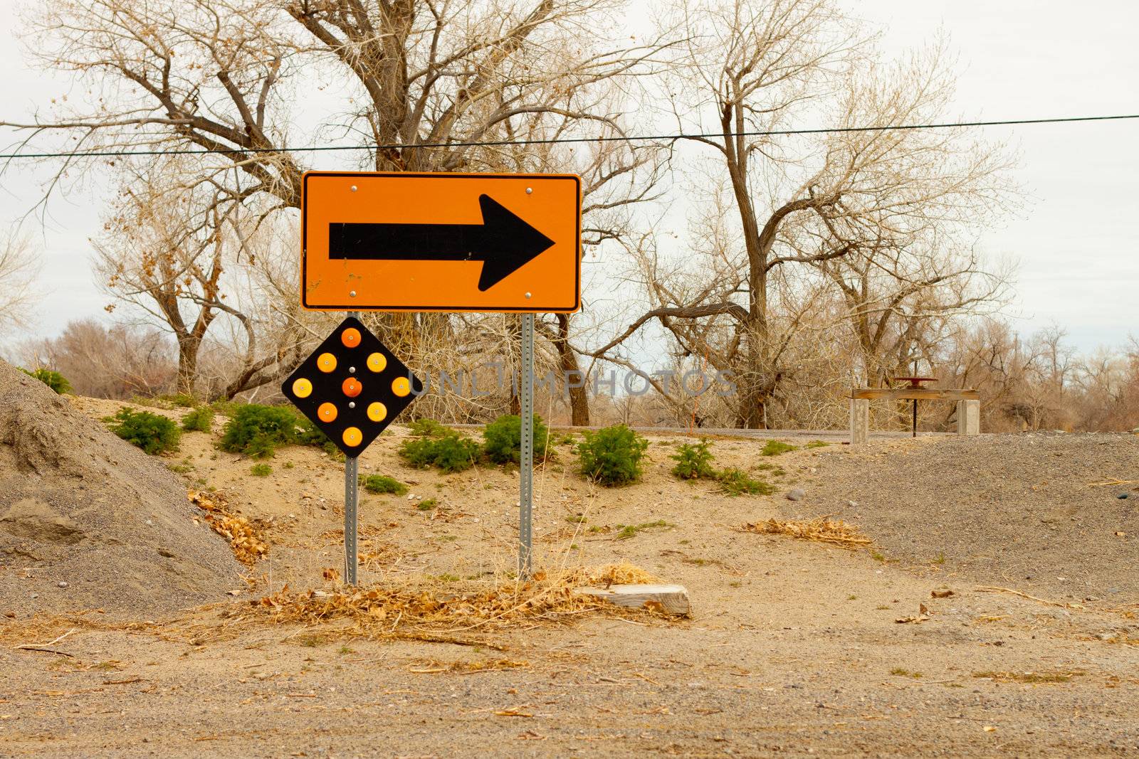 A photograph of a yellow arrow sign.  The sign is telling the viewer to turn right.