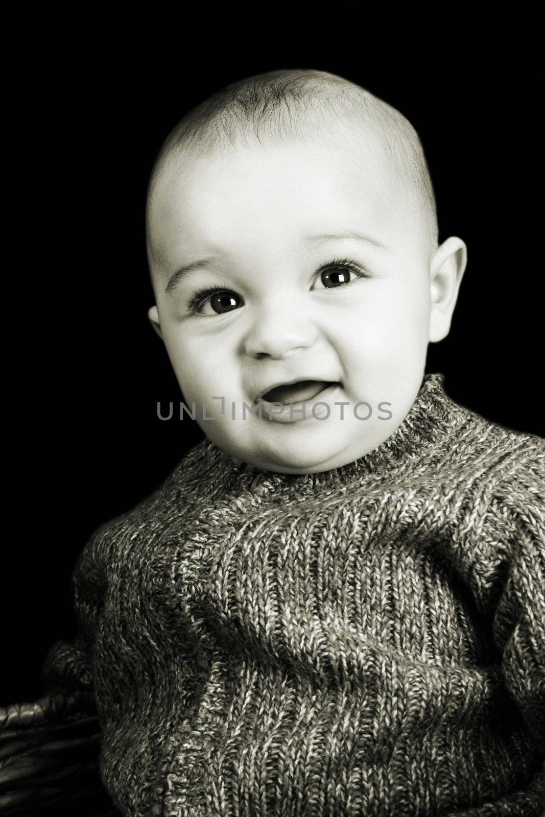 Baby boy against a dark background with a cute expression