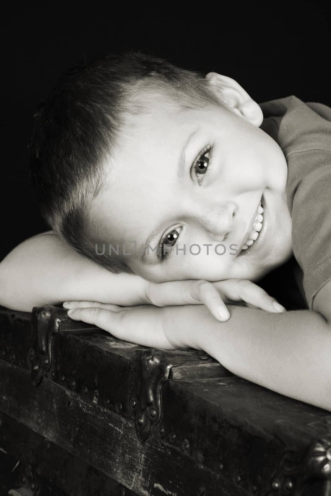 Beautiful blond boy lying on an antique trunk