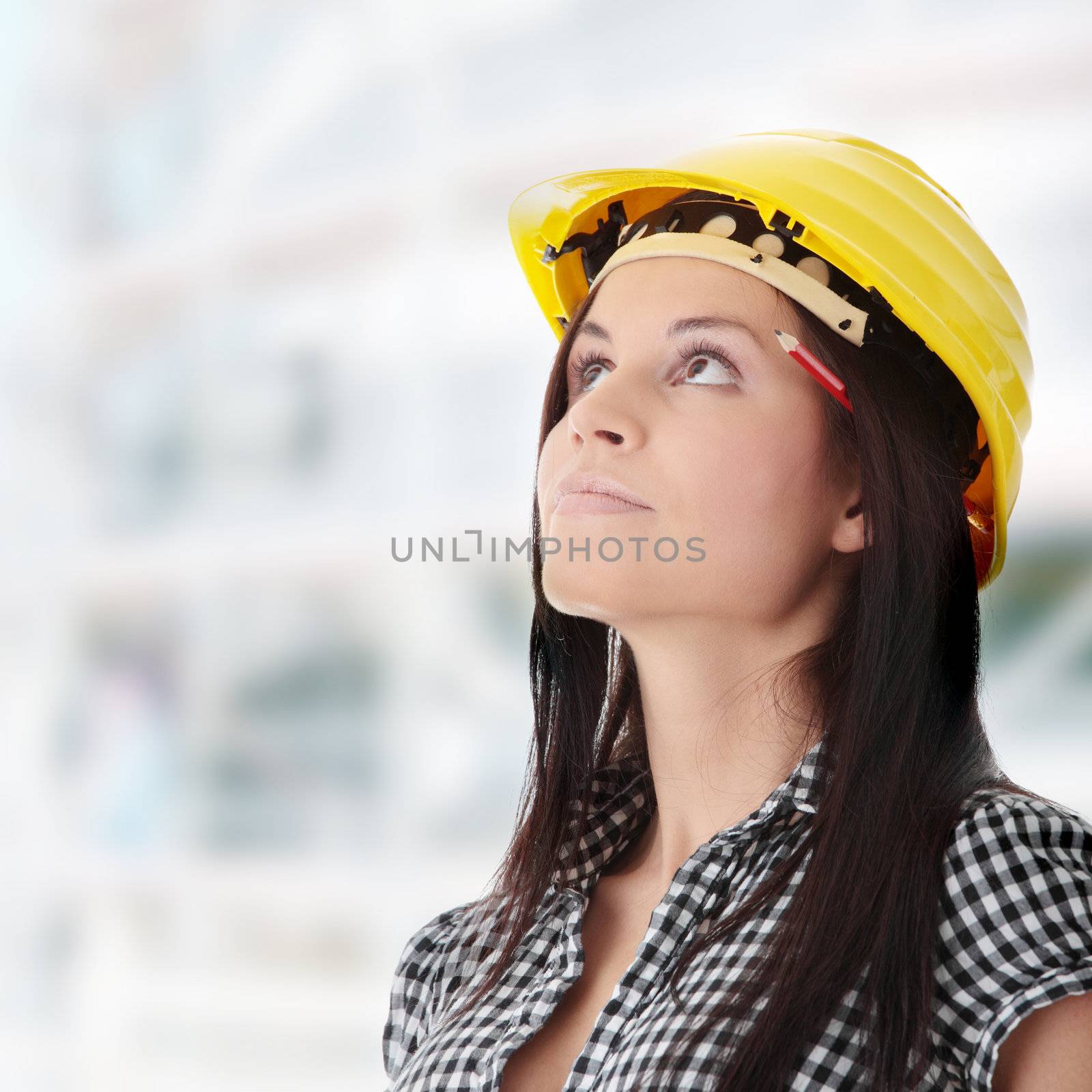 Engineer woman in yellow helmet looking up