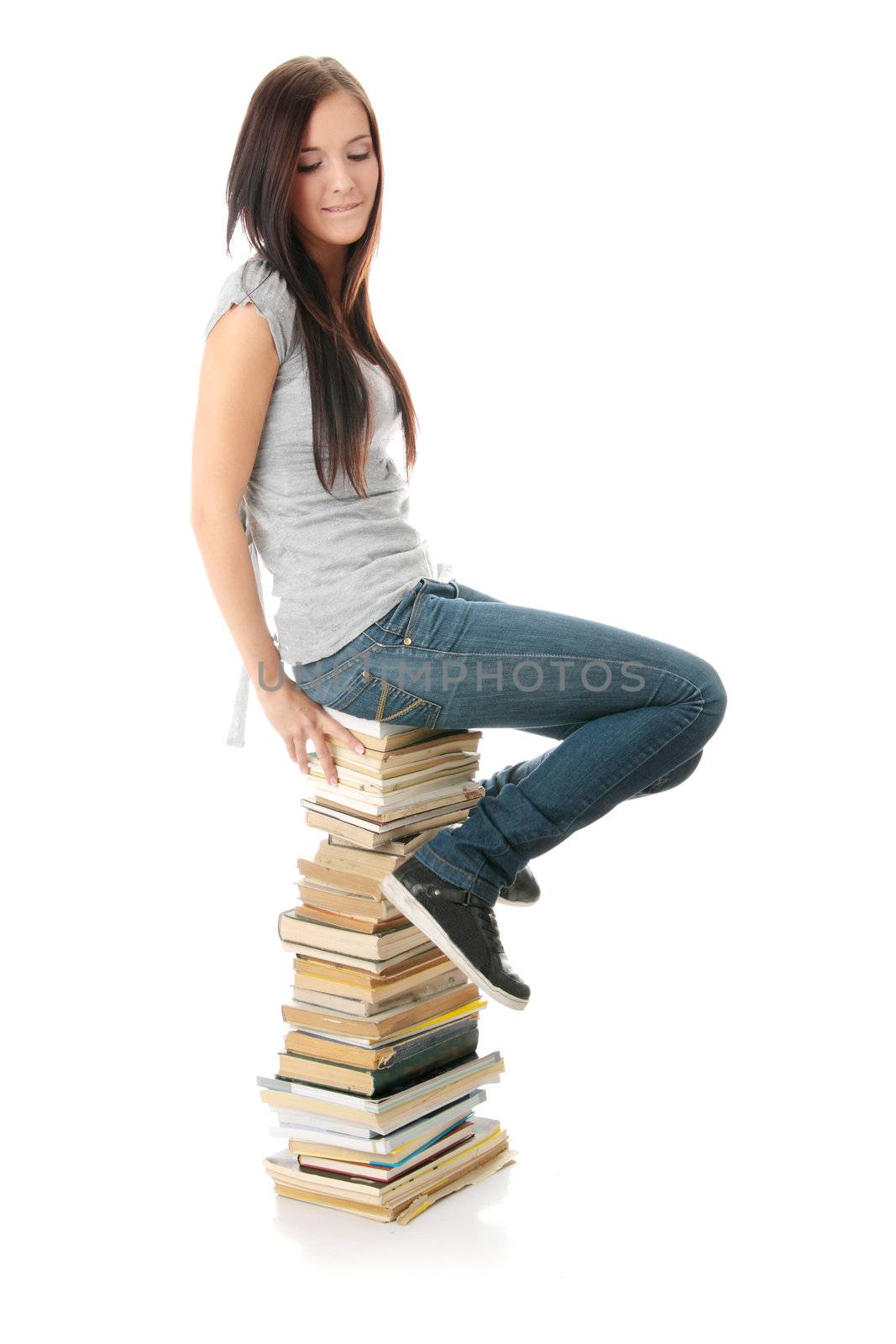 Young teen woman sitting on books isolated