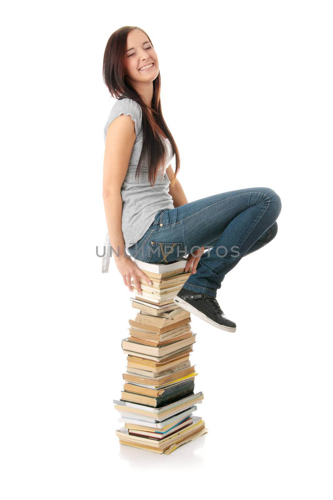 Young teen woman sitting on books isolated
