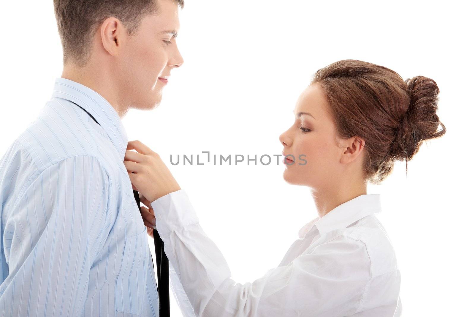 Businesswoman knotting the necktie of the businessman, helping and assisting him getting dressed. Isolated over white.