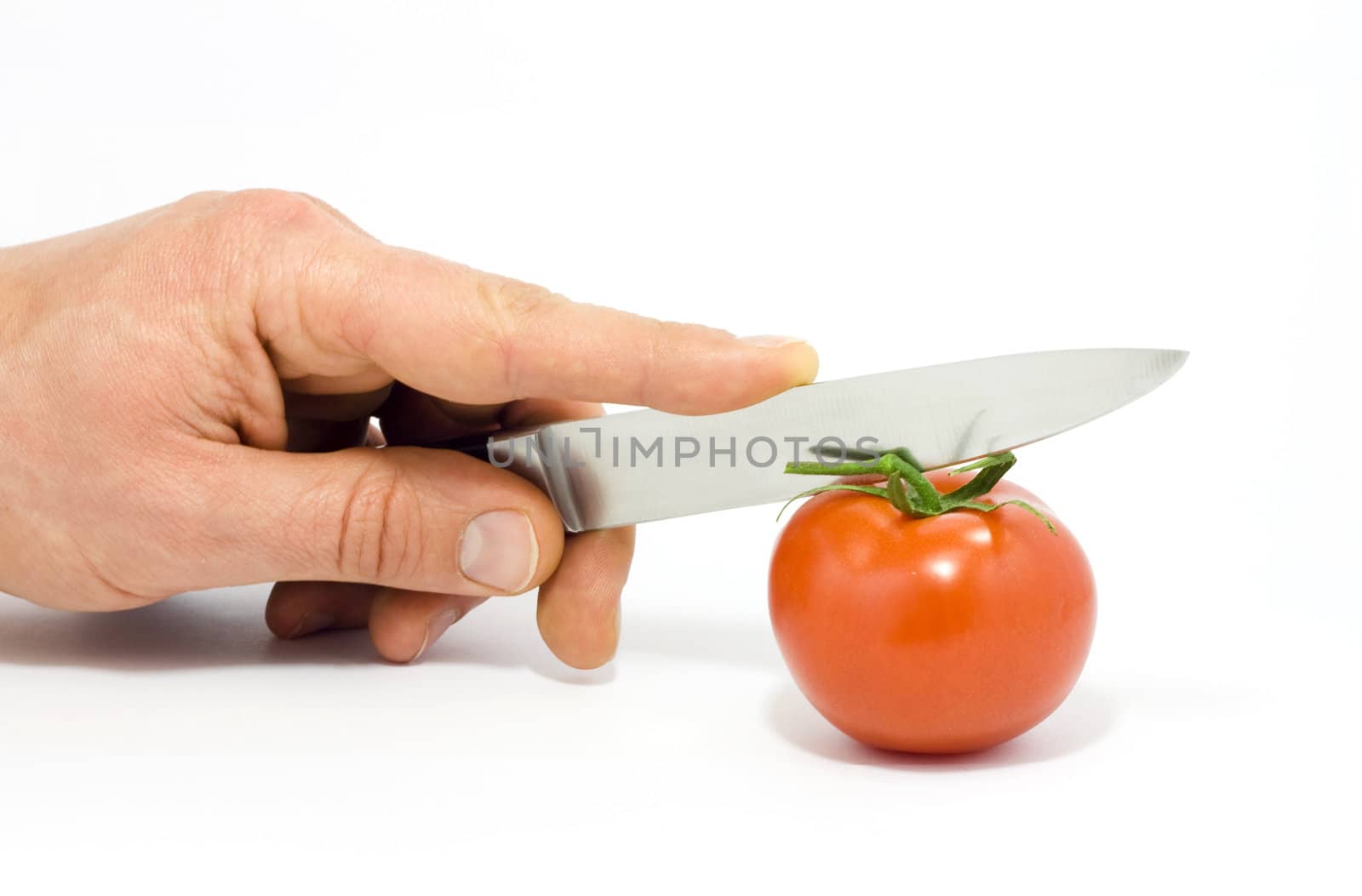 A hand with knife and tomato isolated on white