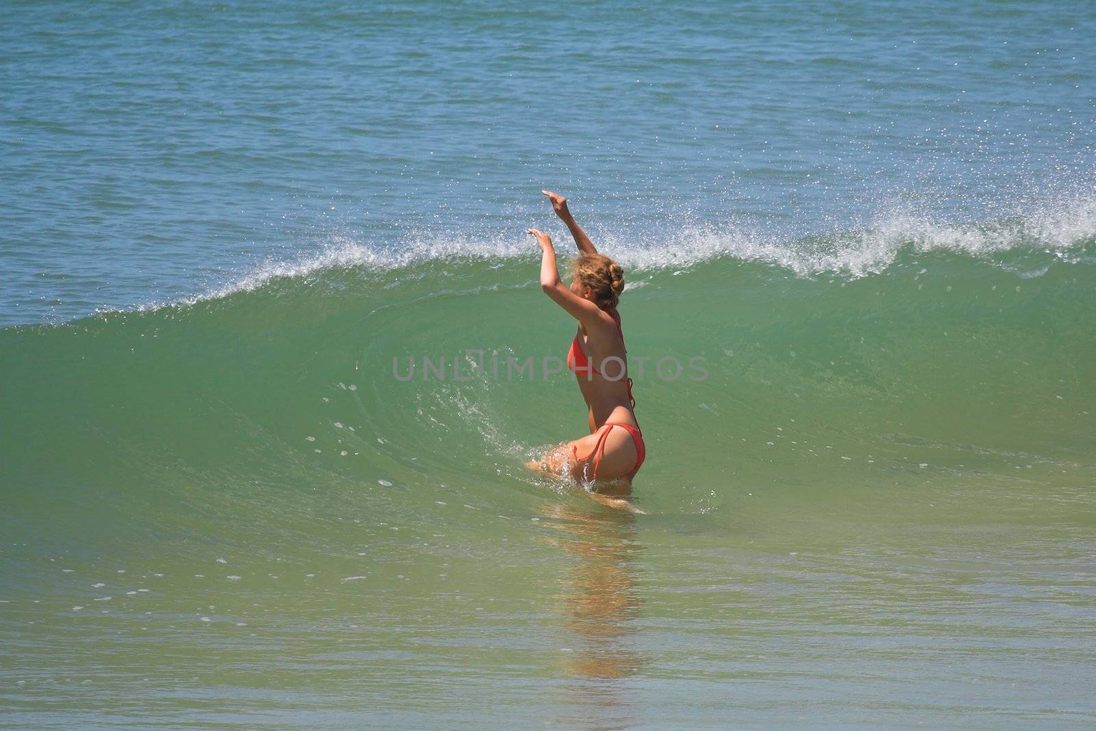 Girl in Orange bikini splashing through a wave