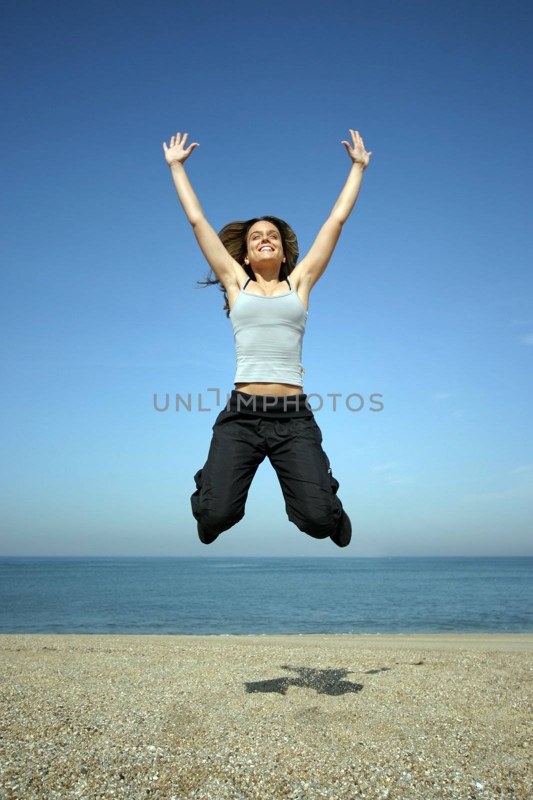 girl jumping on the beach withe blue sky