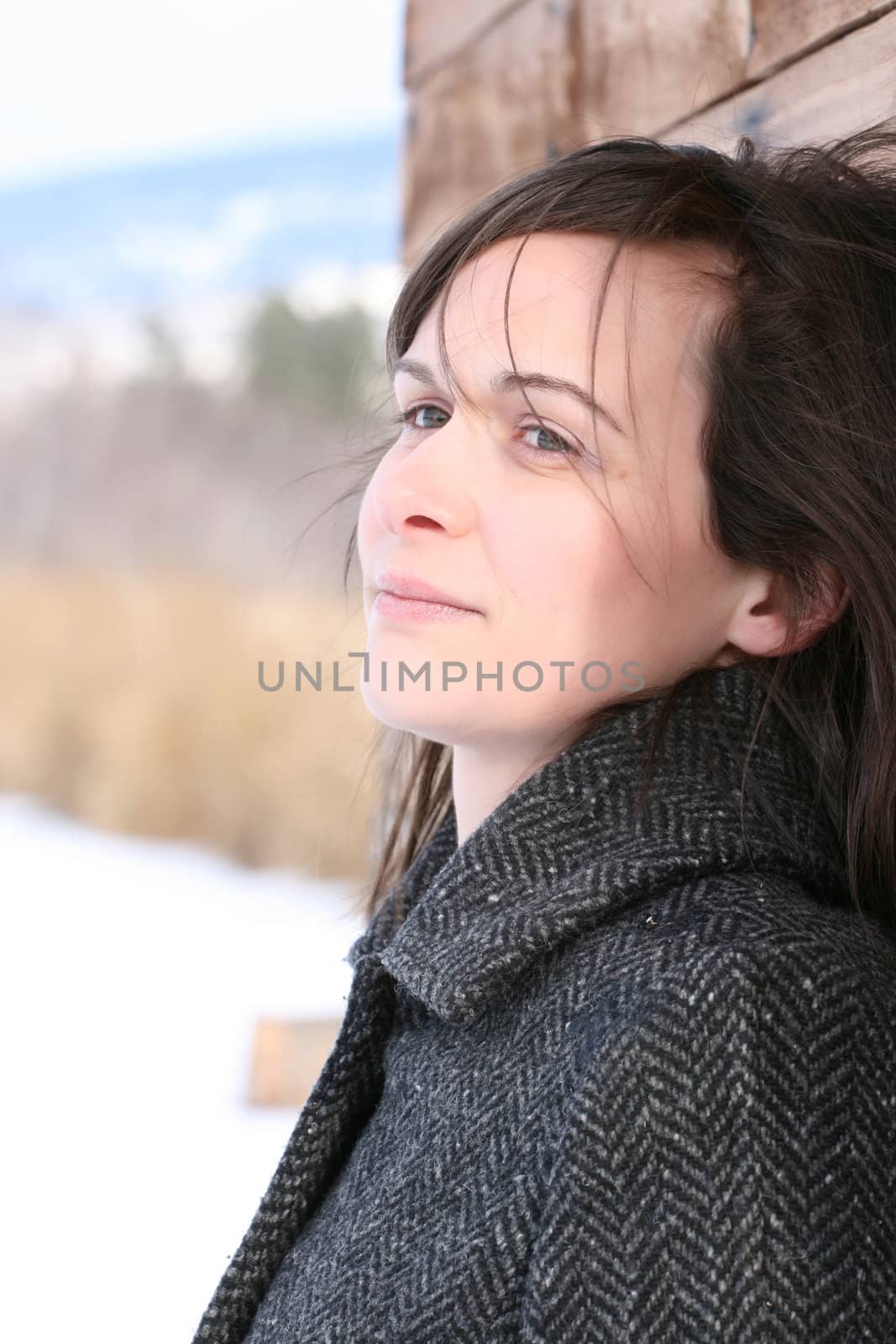 Beautiful brunette female leaning against wooden barn