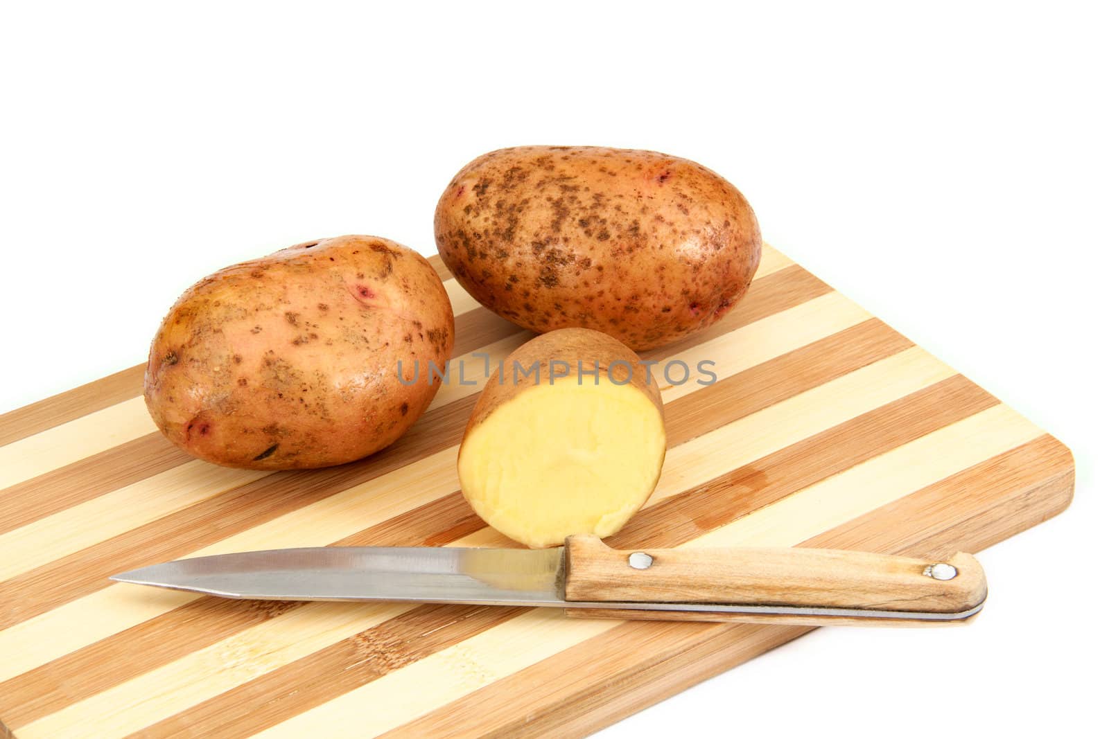Raw potato tubers lying on a cutting board, isolated on a white background
