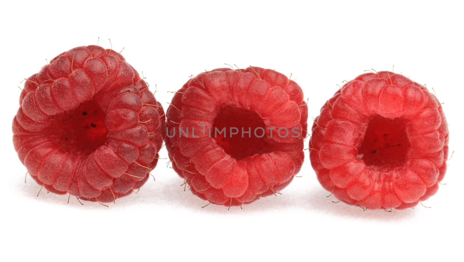 Macro shot of three raspberries photographed in a studio against a white background.