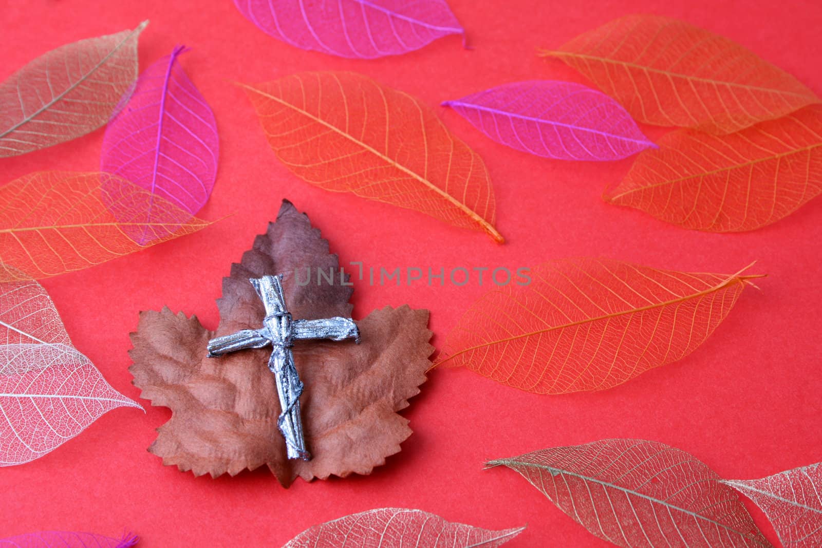 Silver cross made from wood amongst autum leaves