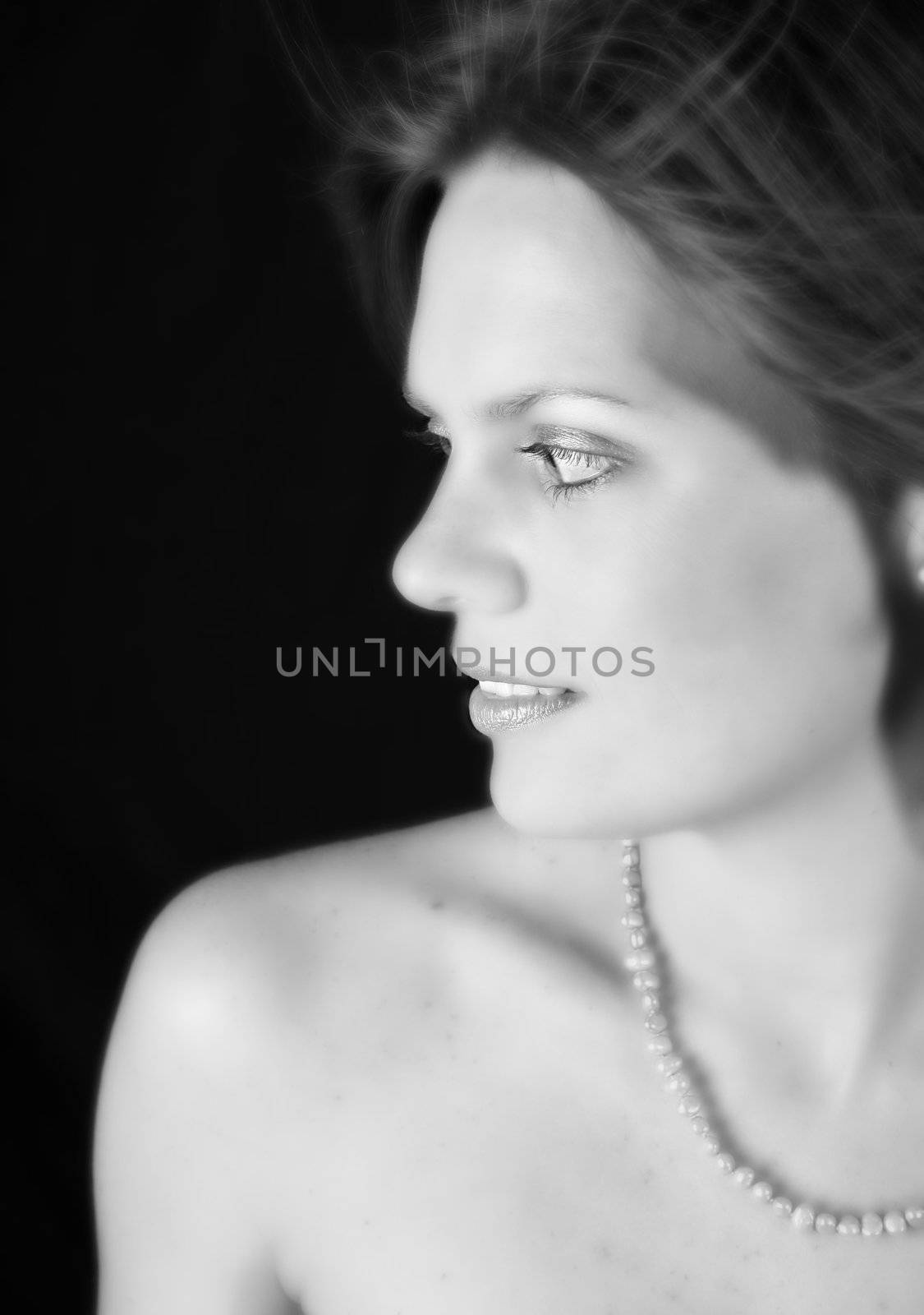Beautiful young woman with bare shoulders wearing pearls