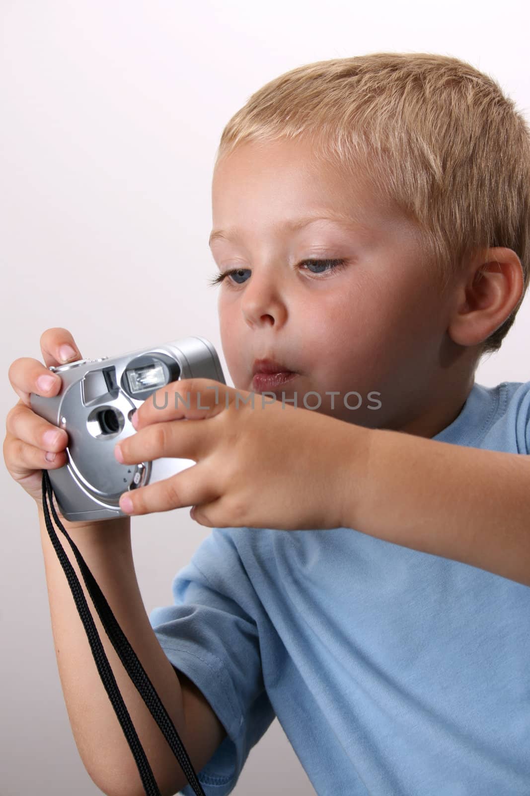Shy toddler holding a silver camera, looking at his object