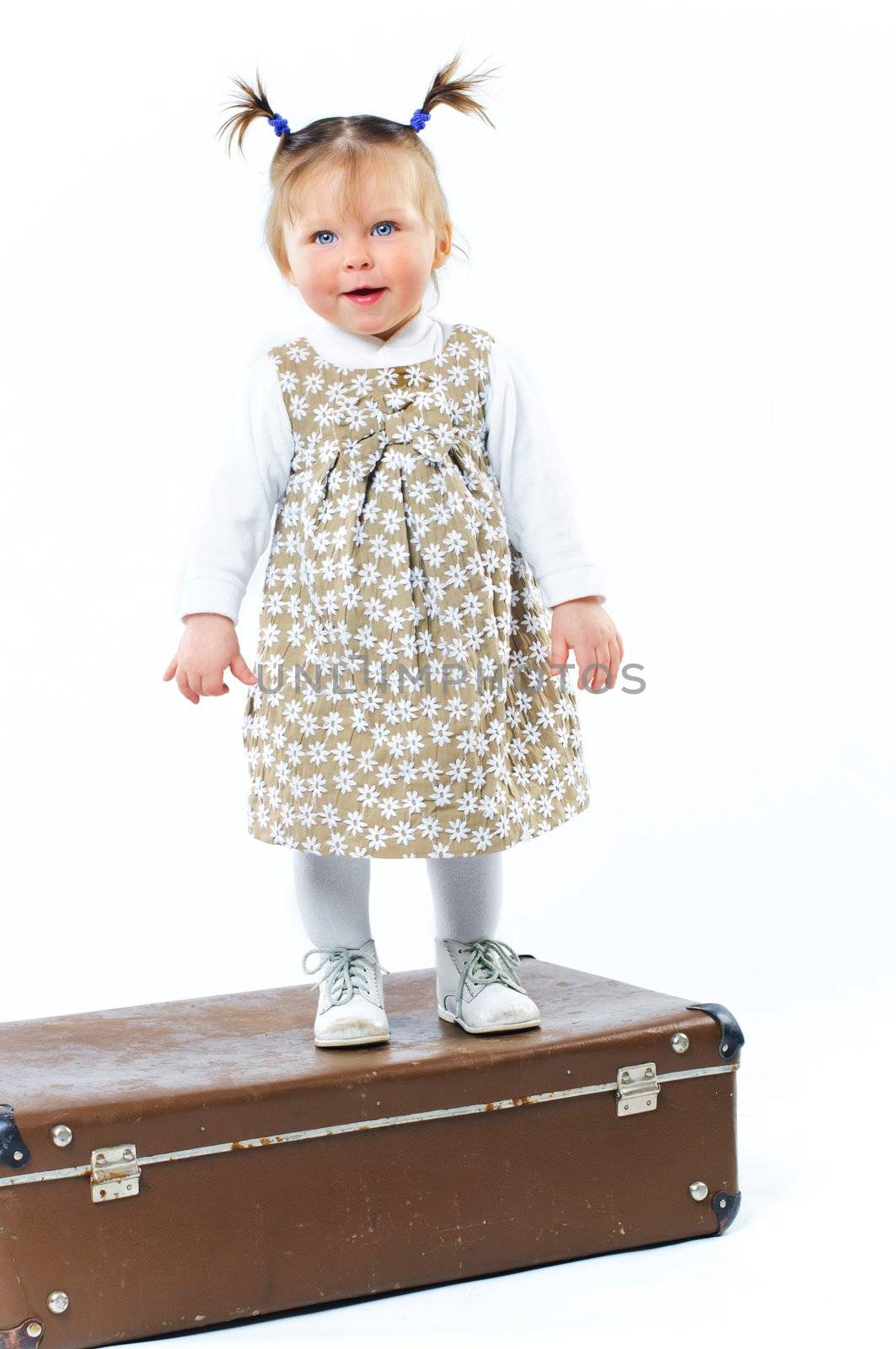 cute baby girl in nude stylish outfit and valise in studio