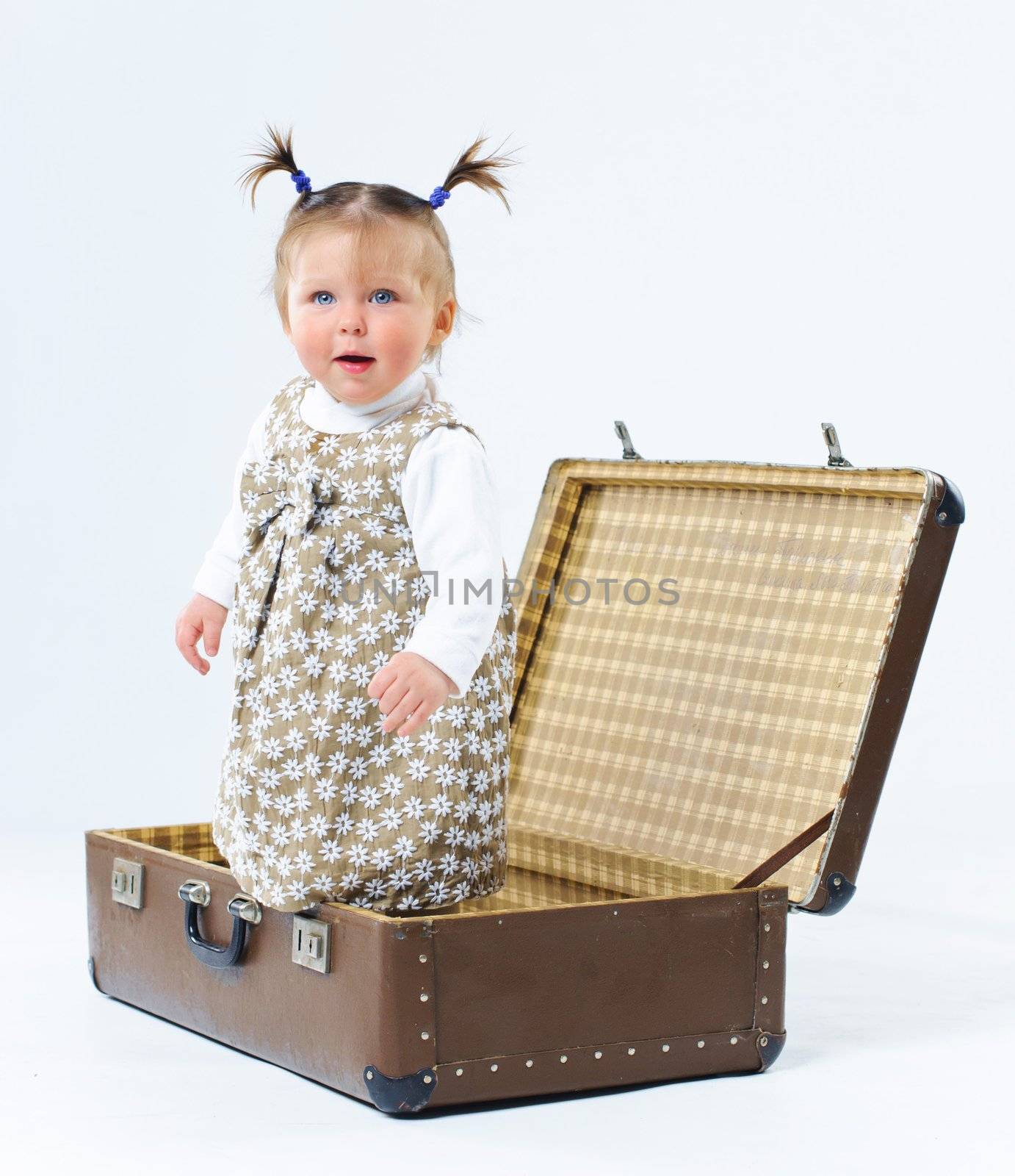 cute baby girl in nude stylish outfit and valise in studio