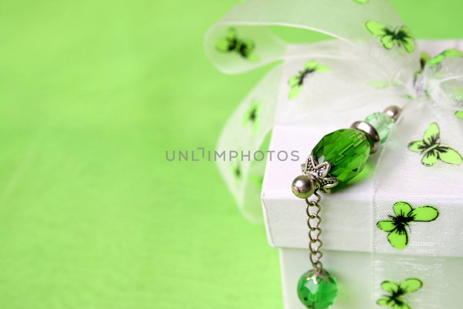 White gift box with green decorations and a crystal pin