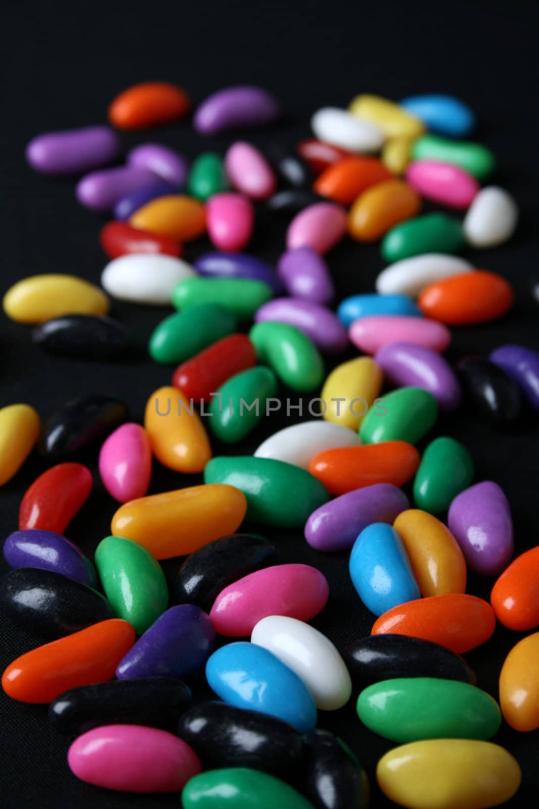 Various colored Jelly Beans scattered on a black background