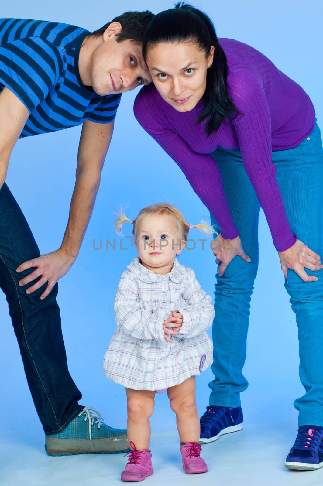 cute baby girl in pink and white stylish outfit with parents in studio