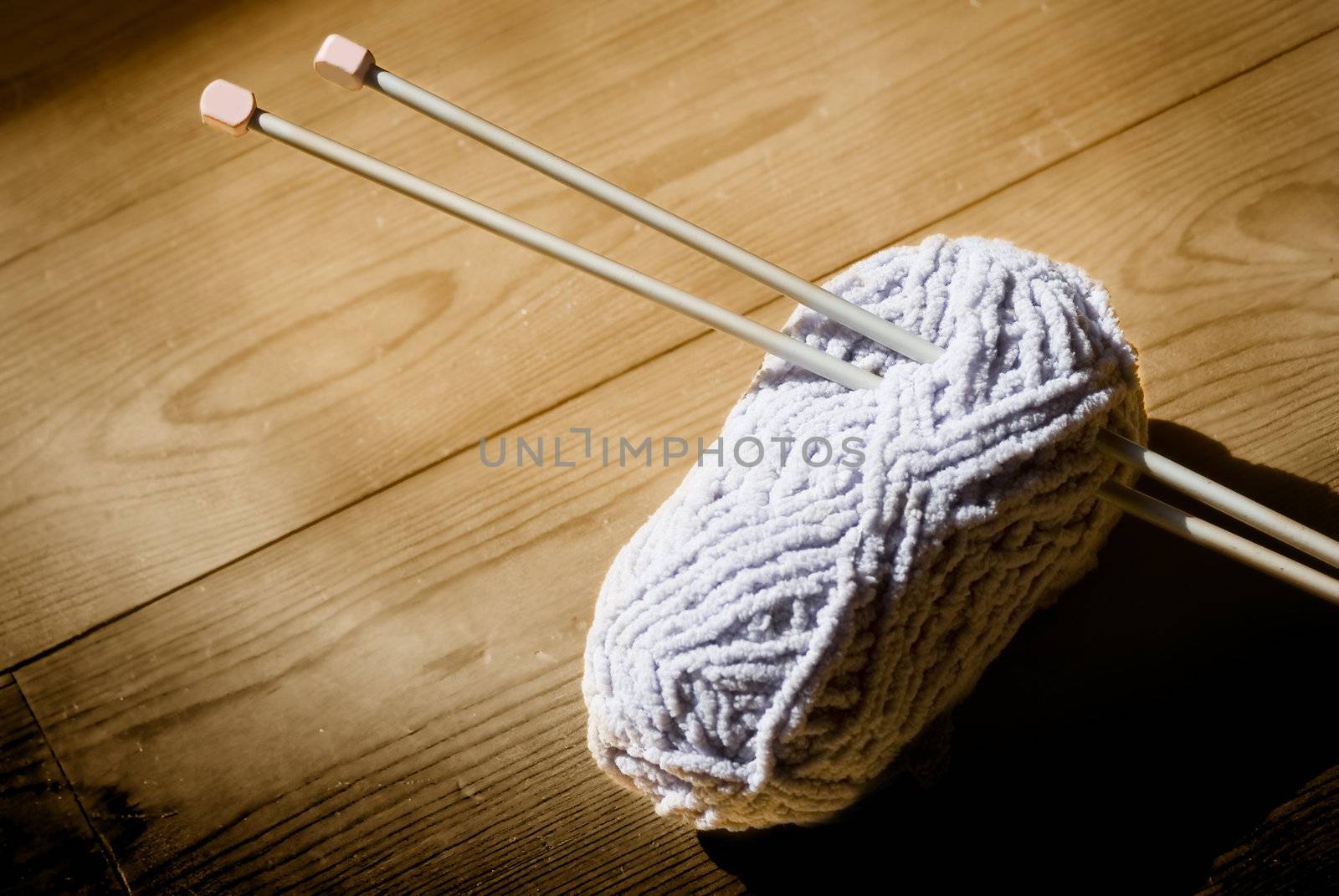 ball of wool and knitting needles on a wooden background in sepia tone 