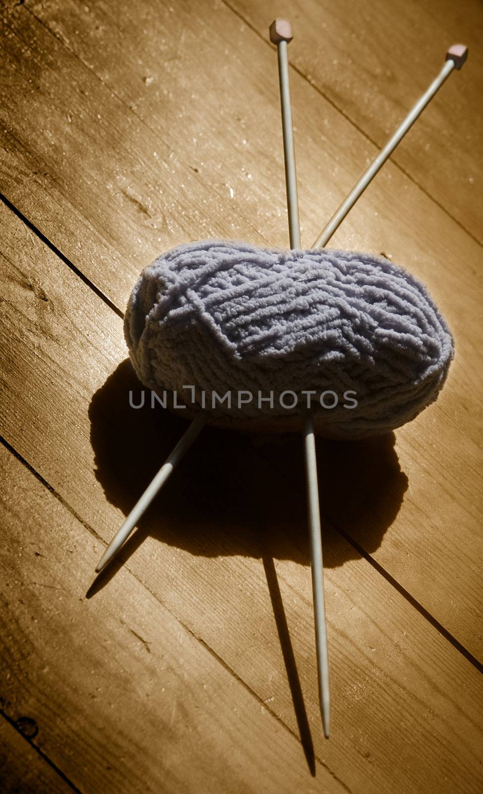 ball of wool and knitting needles on a wooden background in sepia tone 