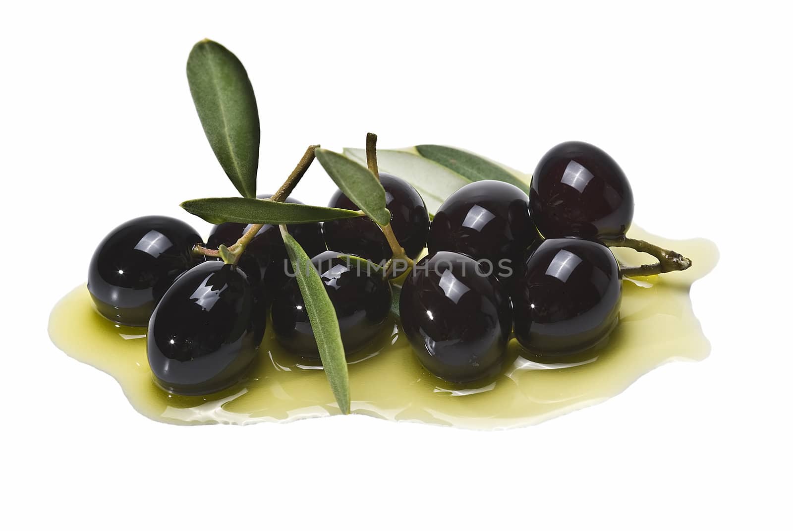 Premium black olives with leaves covered in olive oil and isolated over a white background.