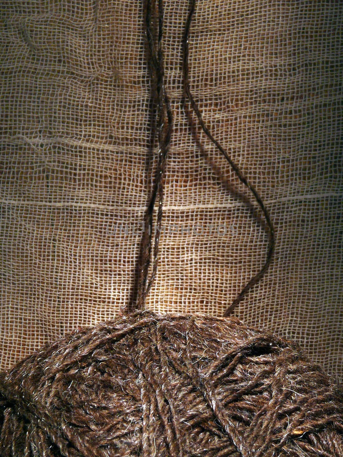 Rough brown thread rising up from the clew on fabric background