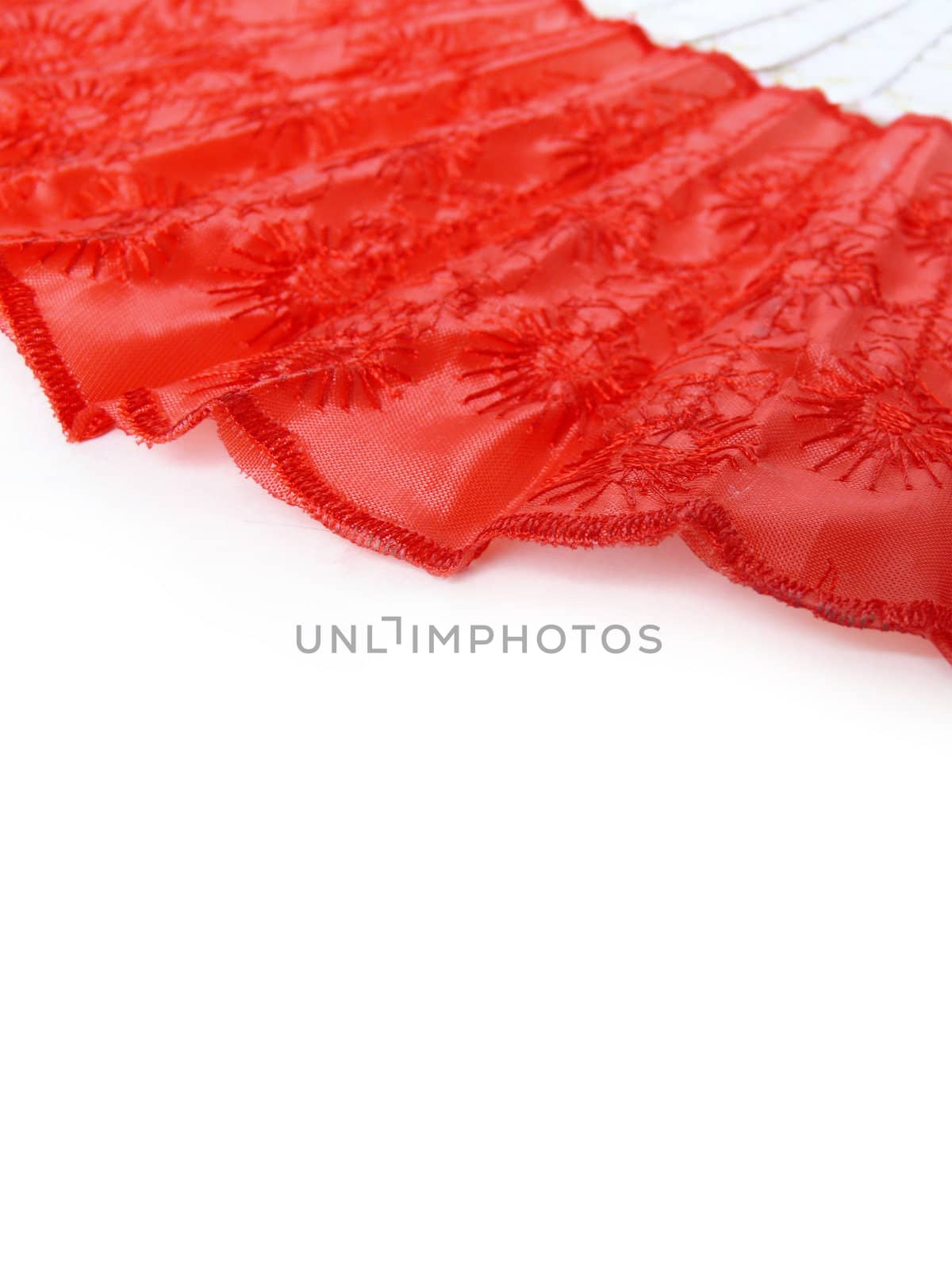 Part of red fan lying on white surface. Abstract red and white background.