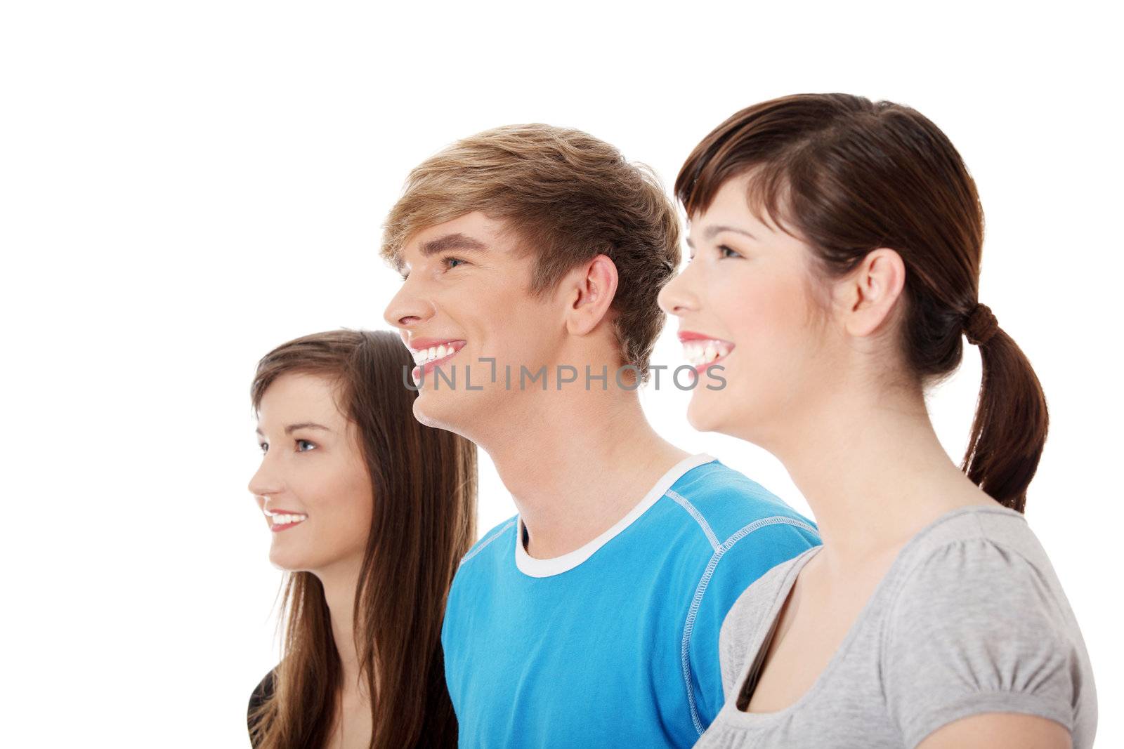 Three young happy friends. Two girls one boy smiling and looking left. Focus on male. Isolated on white background.