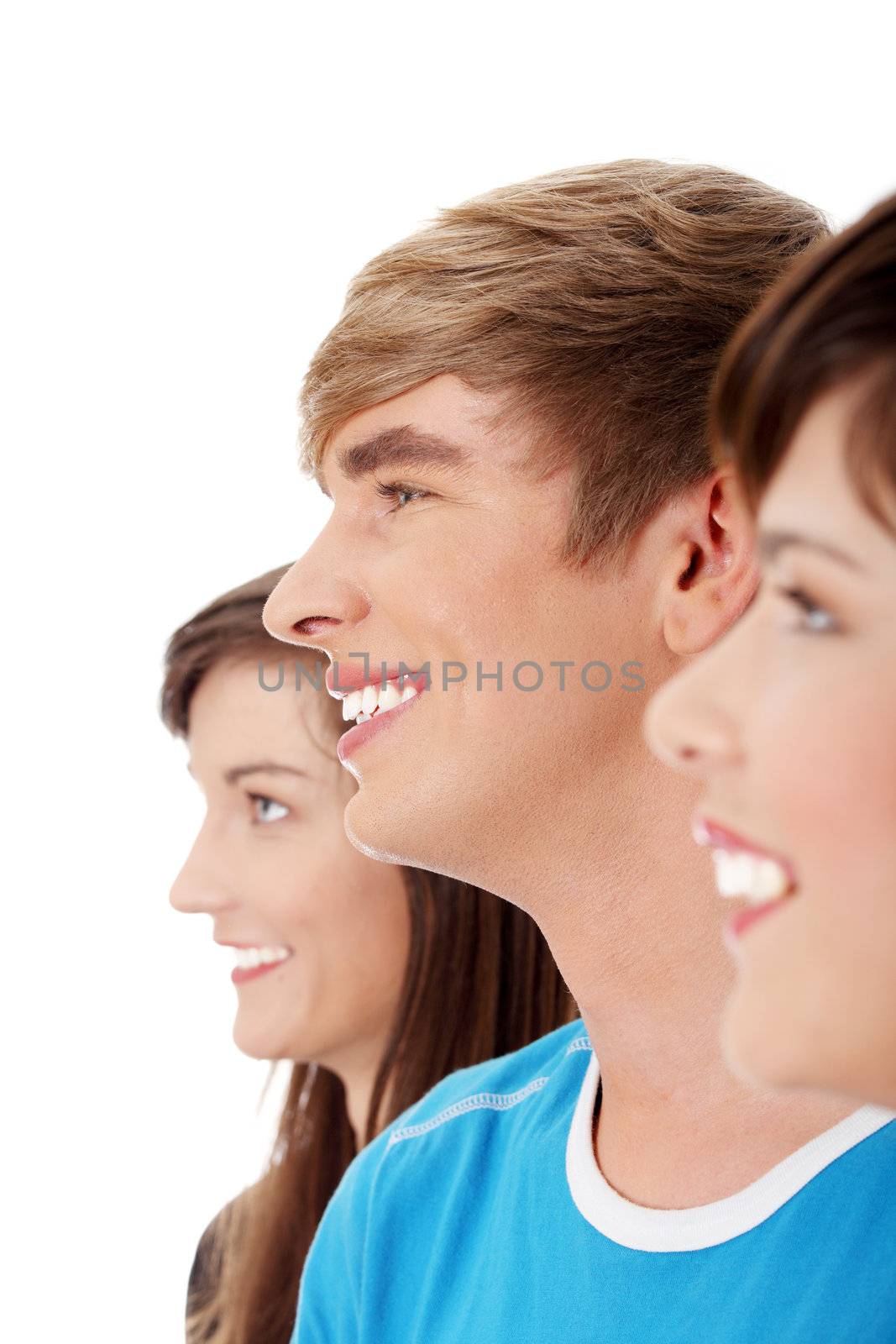 Three young happy friends. Two girls one boy smiling and looking left. Focus on male. Isolated on white background.