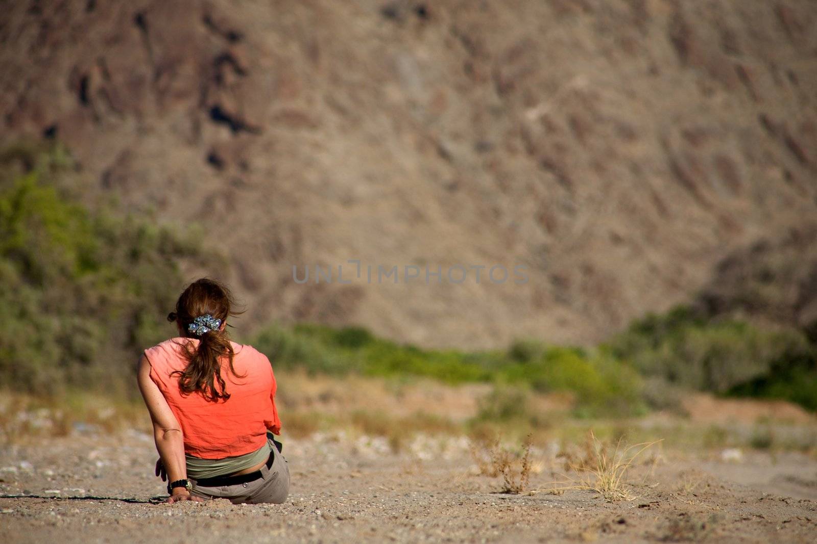 Women alone sitting in the bush somwhere in Namibia wit a red t-shirt and a blurred background