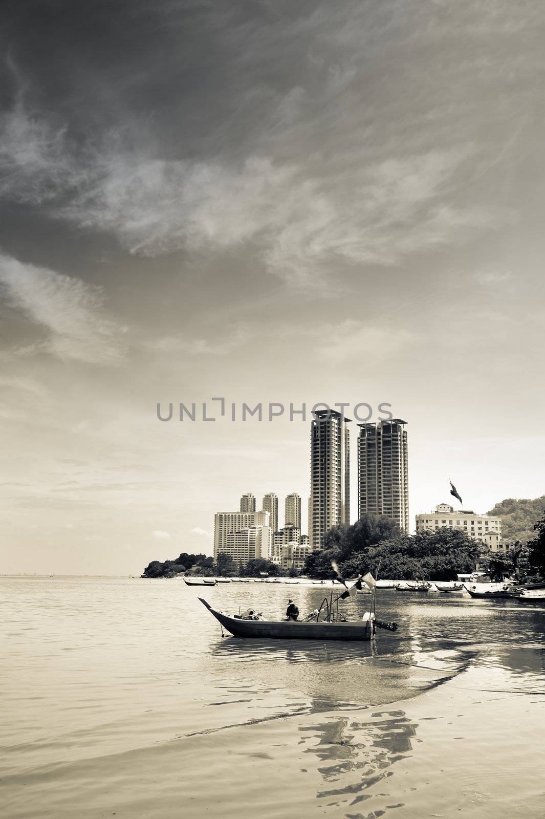 Bay in city with boats and skyscraper under dramatic sky.