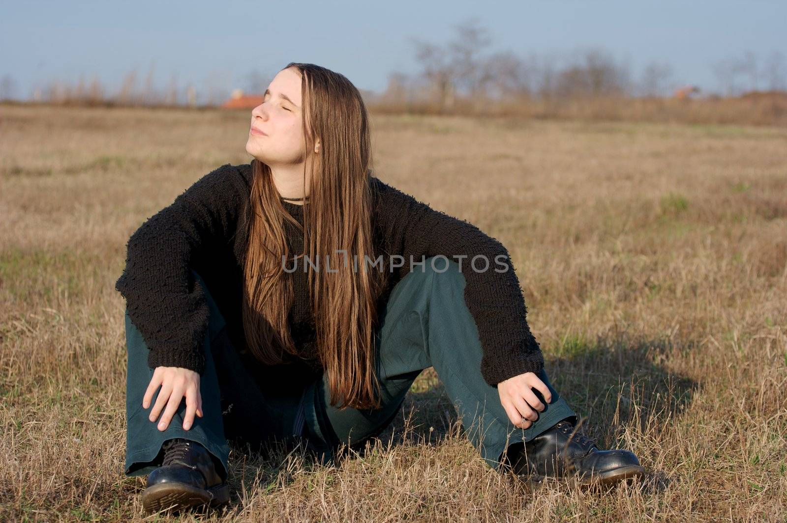 Girl sitting on a dry field