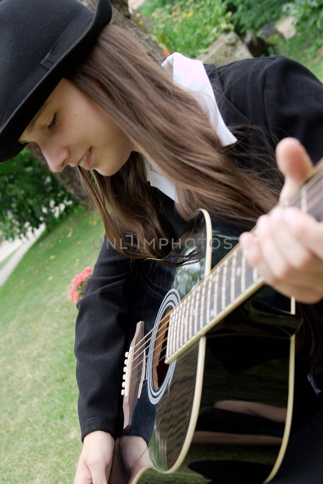 Girl playing acoustic guitar out in the grass