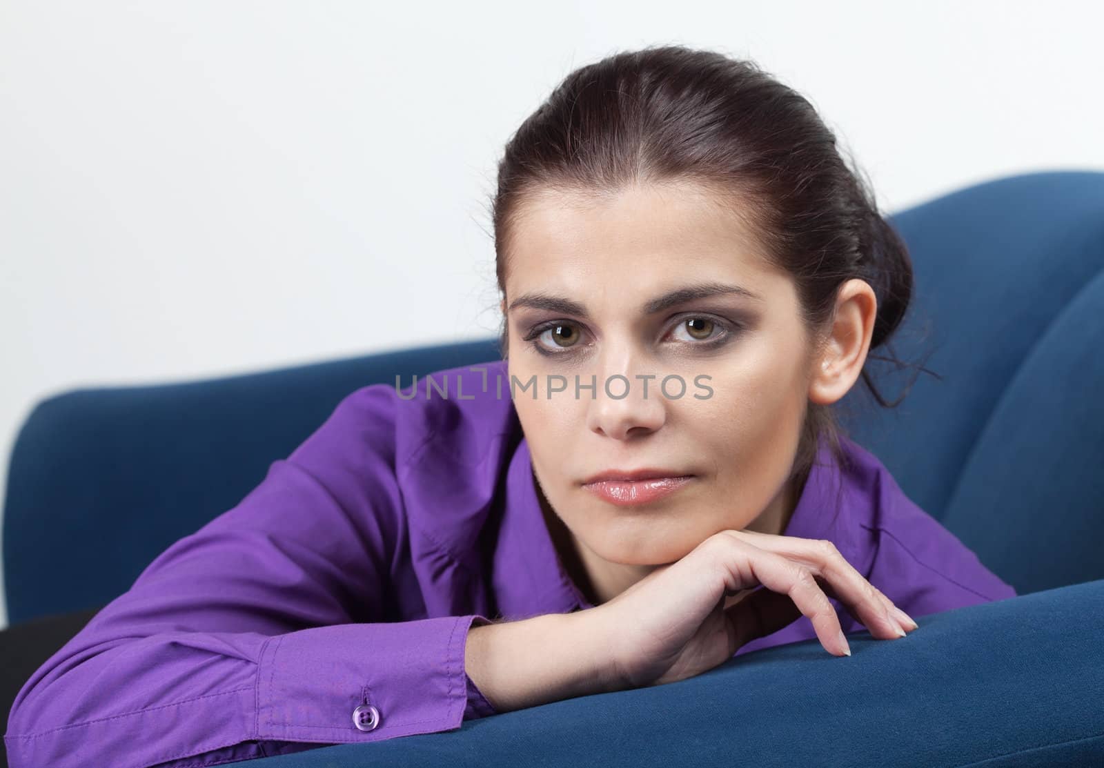 Pretty young brunette woman resting on blue couch