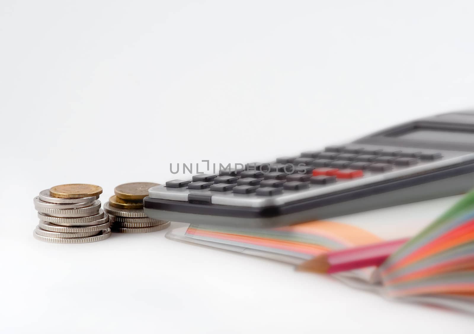 Coins,calculator,notebook and a pen over white background