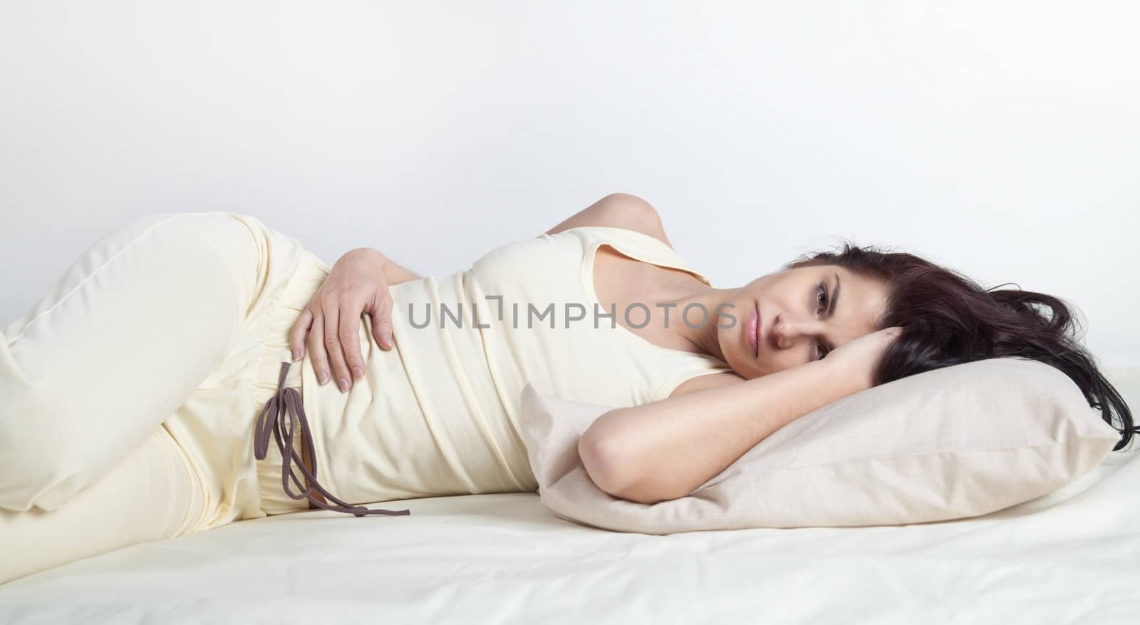 Pretty young brunette woman lying in bed