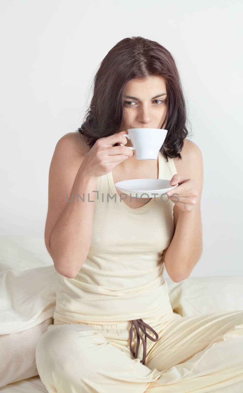 Young woman in bed holding a cup of coffee after she waken up